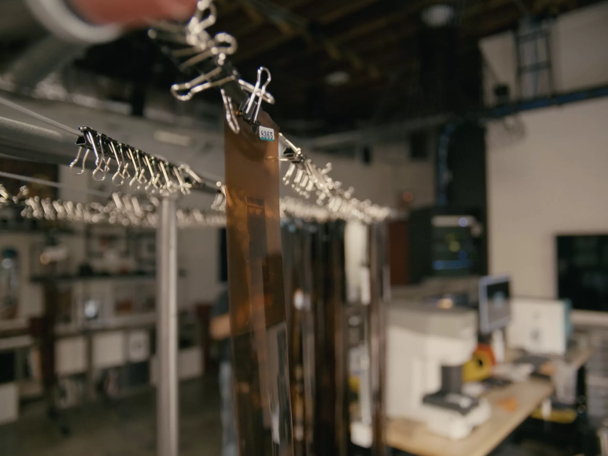 Developed film strips hanging from clips to dry in the lab